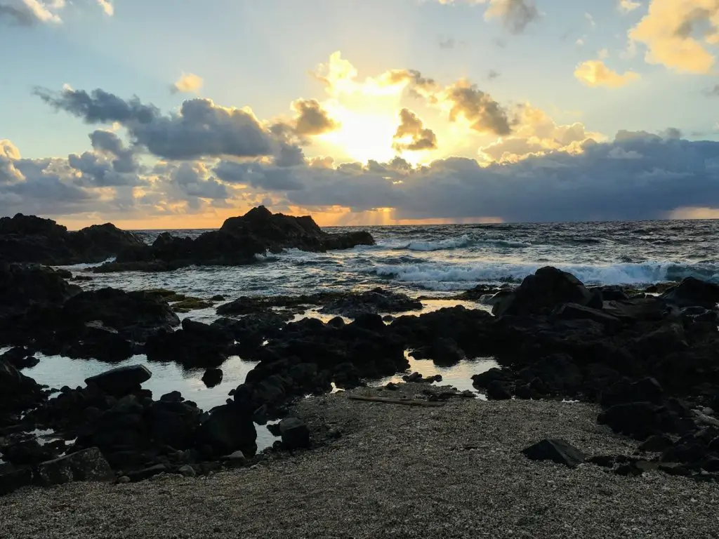rocky ocean by natural pool in aruba at sunrise