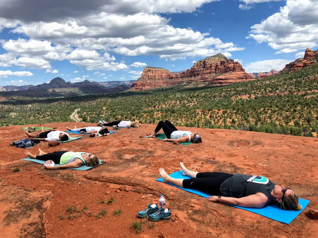 group doing yoga on baby bell red rocks on Sedona Arizona 