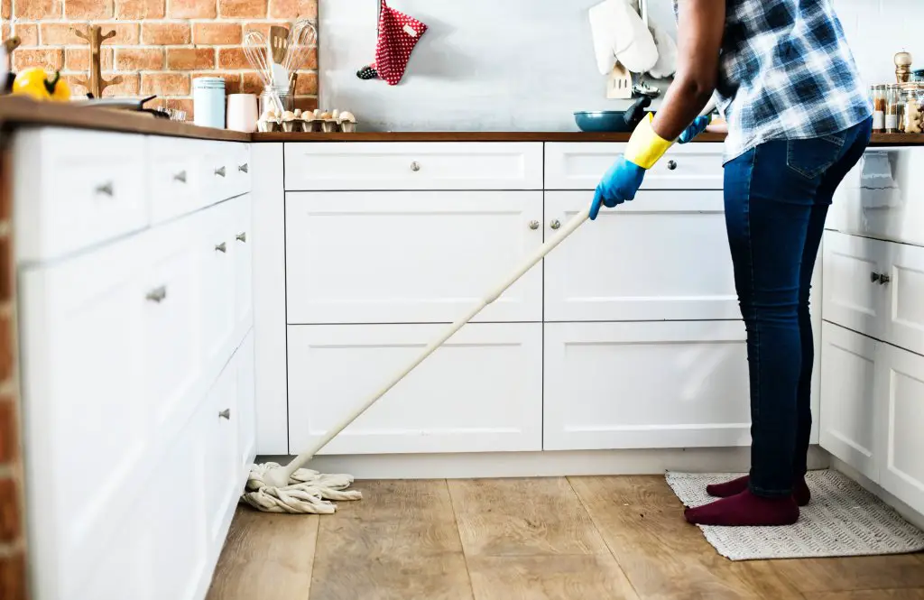 man mopping the kitchen floor before traveling