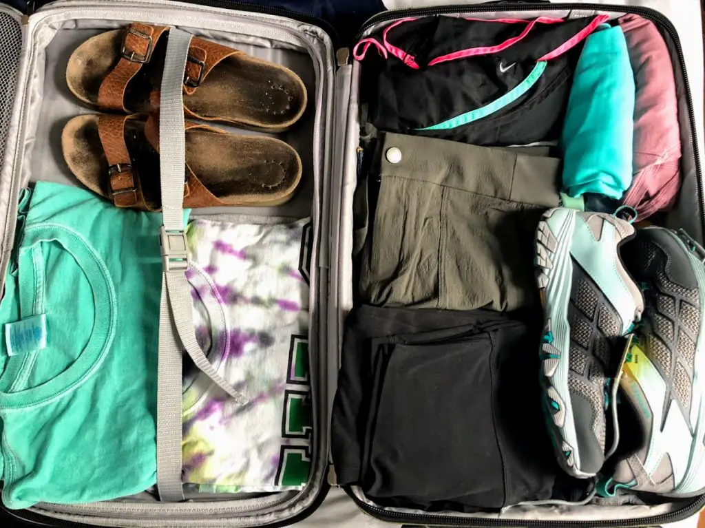 prepare for travel with packed suitcase with clothes and shoes