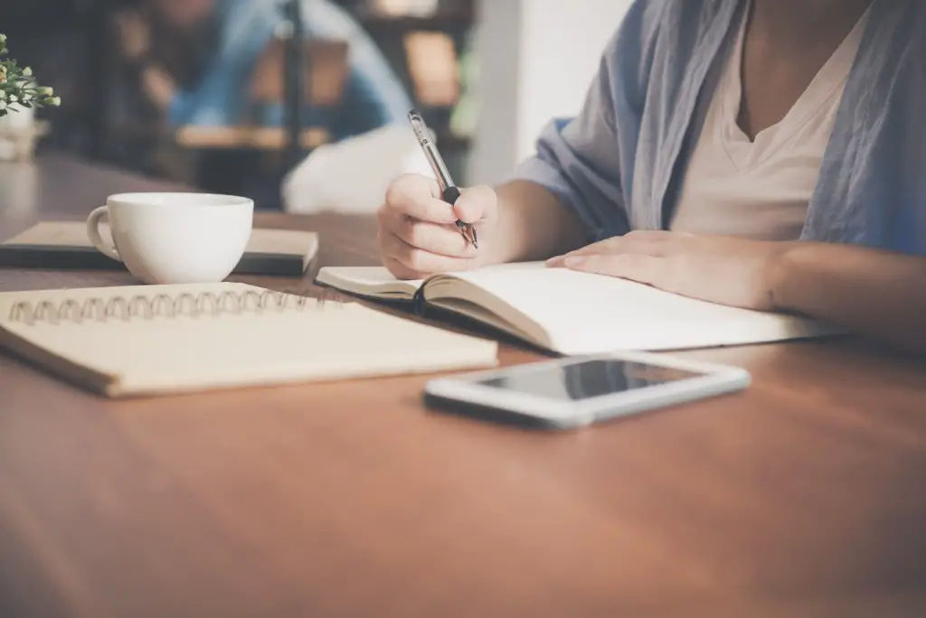 girl writing a budget to save to travel